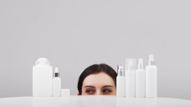 美丽的年轻的高加索女人与完美的健康的皮肤提出了一种产品 带有白色标签的化妆品瓶 美容博客 沙龙概念 简约主义品牌包装模型 — 图库视频影像