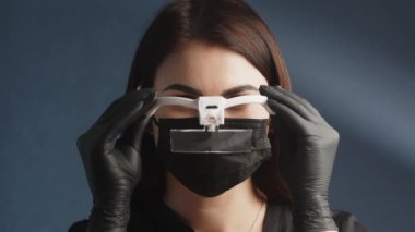 Koruyucu maske takan ve yüzüne özel gözlük takan bir kadın kozmetikçinin yüzünü yakından çek. Spa, rahatlama, tıbbi ya da kozmetoloji çalışanı.