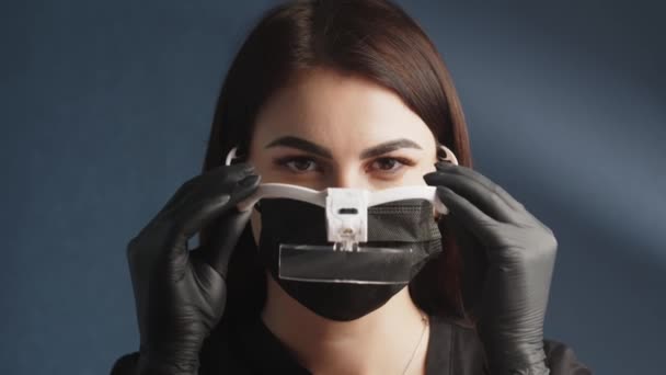 保護マスクを着用し 顔に特別なメガネをかけている女性の化粧師の顔のクローズアップ リラクゼーション 化粧品の労働者 — ストック動画