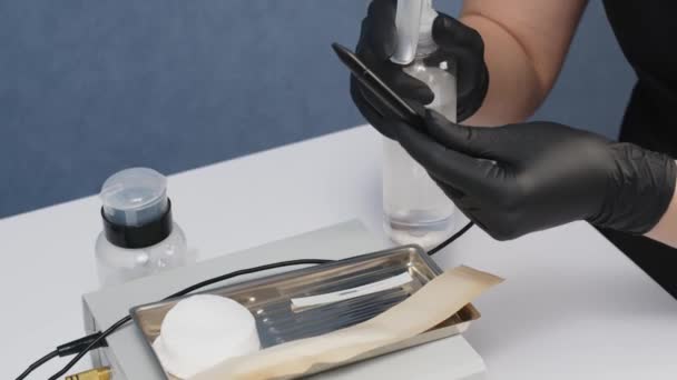 一位戴黑色手套的美容师在美容院里准备了一根电解针 电动除毛器 仪表盘脱毛装置 — 图库视频影像