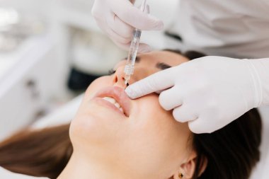 Doktor kozmetik uzmanı güzellik salonundaki güzel bir kadının dudak büyütme prosedürünü yapıyor. Kozmetoloji cilt bakımı. Yüksek kalite fotoğraf