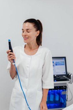 Orta yaşlı güzellik uzmanı yüz gerdirme ve deri sıkma işlemi için ultrason cihazı tutuyor. Genç kadın kozmetolog klinikte modern kozmetoloji ekipmanları kullanıyor.