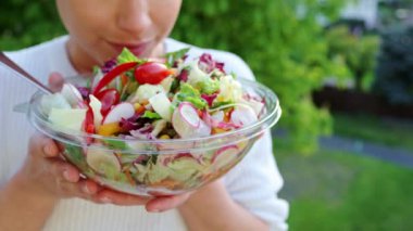 Şef sebze salatası pişiriyor. Salatalık, domates ve turpları karıştıran bir kadın. Sağlıklı beslenme alışkanlıkları, diyet, vejetaryen yemekleri.
