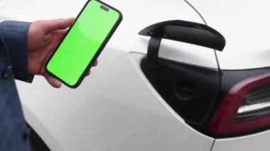 Erkek şarj pilleri, aktif hale getirmek için kromakey ekran telefon kullanır. Yeşil ekranı kapat. Cep telefonundaki krom anahtarı taklit et. Mobil uygulamalı elektrikli araba şarj istasyonu.
