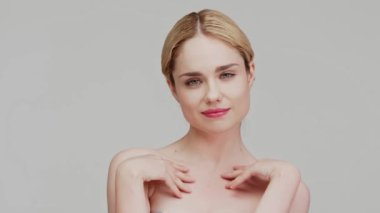 Beautiful smiling blonde female with bare shoulders relaxing, posing at white studio background. Beauty portrait and skincare concept. Copy space, banner. Facial treatment, Cosmetology, glow skin