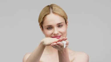 Nemlendirici köpük kullanan sarışın genç bir kadının portresi. Taze nemlendirilmiş ten, güzel kozmetik yüz, mutlu sağlıklı model kavramı.. 