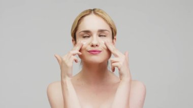 Güzel bir kadın yüzüne nemlendirici sürüyor. Güzellik konsepti