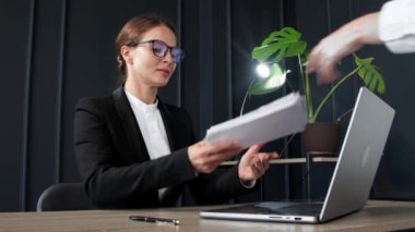 Modern ofisinde çalışan iş kadını kendisine getirilen belgeleri veya faturaları inceliyor. Profesyonel iş temaları, ofis verimliliği ve mali yönetim için ideal.