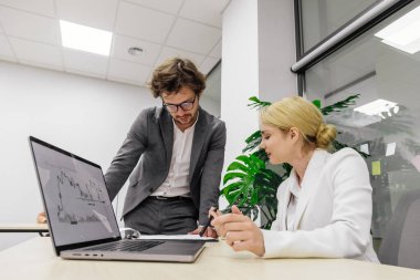 Modern bir ofiste iş arkadaşları birbirlerine danışıyorlar, proje detayları ve finansal stratejiler planlıyorlar. Takım çalışması, proje yönetimi ve iş planlama temaları için ideal.