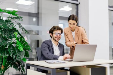 Modern bir ofiste mali analiz için dizüstü bilgisayar kullanan bir iş ekibi. İş adamı ve iş kadını beyin fırtınası yapıyor ve şirket projesini tartışıyor, çözümler üzerinde işbirliği yapıyorlar. Takım çalışması ve finansal strateji temaları için mükemmel.       