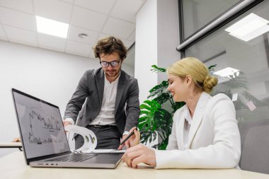 Modern bir ofiste iş arkadaşları birbirlerine danışıyorlar, proje detayları ve finansal stratejiler planlıyorlar. Takım çalışması, proje yönetimi ve iş planlama temaları için ideal.