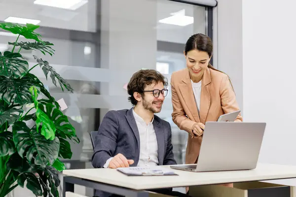 Modern bir ofiste mali analiz için dizüstü bilgisayar kullanan bir iş ekibi. İş adamı ve iş kadını beyin fırtınası yapıyor ve şirket projesini tartışıyor, çözümler üzerinde işbirliği yapıyorlar. Takım çalışması ve finansal strateji temaları için mükemmel.       