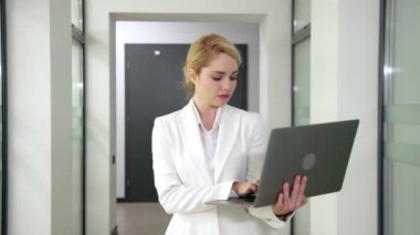 Modern ofis odasında dizüstü bilgisayar kullanan kendine güvenen bir iş kadını.. 