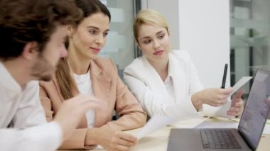 Modern bir ofiste iş arkadaşları birbirlerine danışıyorlar, proje detayları ve finansal stratejiler planlıyorlar. Takım çalışması, proje yönetimi ve iş planlama temaları için ideal.