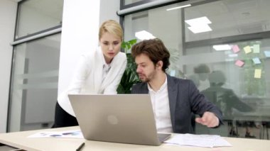 Modern bir ofiste iş arkadaşları birbirlerine danışıyorlar, proje detayları ve finansal stratejiler planlıyorlar. Takım çalışması, proje yönetimi ve iş planlama temaları için ideal.