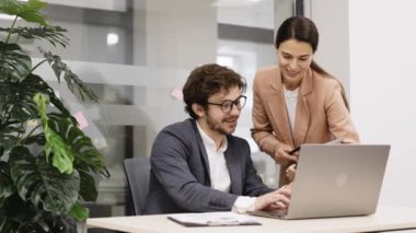 Direktör ve meslektaşım online iş hizmetlerini ve kurumsal yazılımı birlikte bir dizüstü bilgisayarda gözden geçiriyorlar. Ofiste liderlik, takım çalışması ve teknoloji danışmanlığı konuları için ideal..