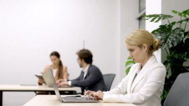 Yönetmen ya da pazarlama müdürü olan şık bir iş kadını, modern bir iş yerinde bilgisayarının başında verimli bir şekilde çalışıyor. Profesyonellik ve çalışma alanı üretkenliği temaları için ideal.