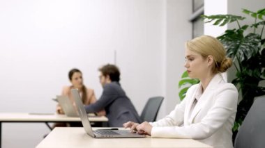 Yönetmen ya da pazarlama müdürü olan şık bir iş kadını, modern bir iş yerinde bilgisayarının başında verimli bir şekilde çalışıyor. Profesyonellik ve çalışma alanı üretkenliği temaları için ideal.