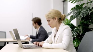 Yönetmen ya da pazarlama müdürü olan şık bir iş kadını, modern bir iş yerinde bilgisayarının başında verimli bir şekilde çalışıyor. Profesyonellik ve çalışma alanı üretkenliği temaları için ideal.