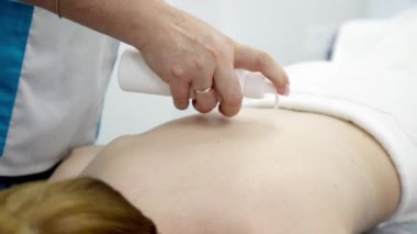 Tecrübeli bir masörün genç bir kadının sırtına hafifçe masaj yapan ellerinin detaylı görüntüsü. Tedavi, rahatlama, vücut bakımı ve sağlık hizmetlerini resmetmek için mükemmel.