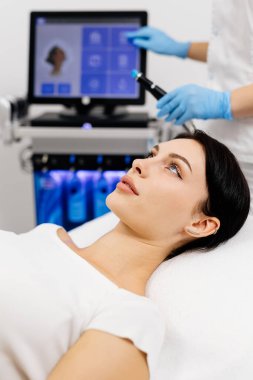 Close-up of cosmetologist hands polishing and cleansing the skin of young woman face using a vacuum machine. Concept of skin care, rejuvenation and cosmetology. clipart