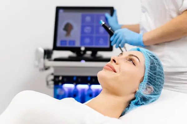 stock image Close-up of cosmetologist hands polishing and cleansing the skin of young woman face using a vacuum machine. Concept of skin care, rejuvenation and cosmetology.