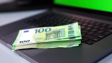 Yakın plan. Açık dizüstü bilgisayarı ve yığınla parası olan işyeri. Etkili para yönetimi. Evden çalış..     
