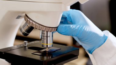 Yüksek teknolojili mikroskop kullanan bilim adamının yakından görüntüsü, bilim adamı örneği modern bir endüstriyel laboratuvarda inceliyor. Bilim ve teknoloji. Testler. Tıbbi deney.      