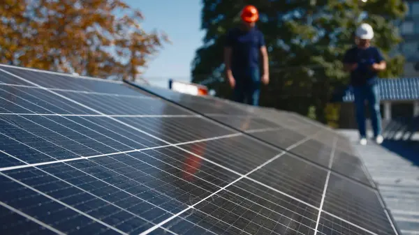 Güneş panellerinin kurulumu, bağlantısı ve montajı. İki işçi güneş panellerini bağlıyor. Teknisyenler metal standa güneş panelleri kuruyor. Bir evin çatısına PV güneş panelleri kuran işçiler.