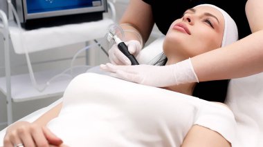 Close-up of cosmetologist polishing and cleansing the skin of young woman skin using a vacuum machine. Concept of skin care, rejuvenation and cosmetology. clipart