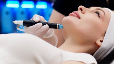 Close-up of cosmetologist polishing and cleansing the skin of young woman skin using a vacuum machine. Concept of skin care, rejuvenation and cosmetology. clipart