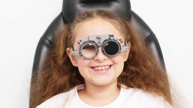 Küçük bir hasta, bir göz hastalıkları kliniğinde modern teşhis ekipmanları kullanan profesyonel bir optometrist tarafından göz testine tabi tutuluyor..
