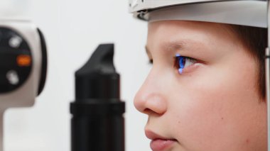 Yarık lamba kullanan çocuğun incelenmesi. Mikroskop ve odaklanmış ışık kaynağı. Merceğin durumunu belirlemek için gözün yüksek hassaslıkta incelenmesi için bir cihaz..