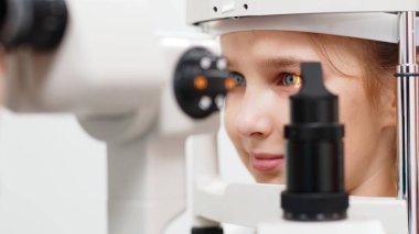 Yarık lamba kullanan çocuğun incelenmesi. Mikroskop ve odaklanmış ışık kaynağı. Merceğin durumunu belirlemek için gözün yüksek hassaslıkta incelenmesi için bir cihaz..