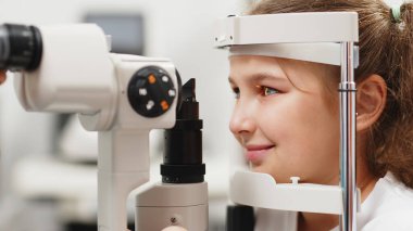 Yarık lamba kullanan çocuğun incelenmesi. Mikroskop ve odaklanmış ışık kaynağı. Merceğin durumunu belirlemek için gözün yüksek hassaslıkta incelenmesi için bir cihaz..