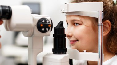 Yarık lamba kullanan çocuğun incelenmesi. Mikroskop ve odaklanmış ışık kaynağı. Merceğin durumunu belirlemek için gözün yüksek hassaslıkta incelenmesi için bir cihaz..