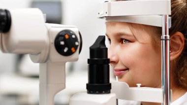 Yarık lamba kullanan çocuğun incelenmesi. Mikroskop ve odaklanmış ışık kaynağı. Merceğin durumunu belirlemek için gözün yüksek hassaslıkta incelenmesi için bir cihaz..