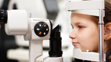 Pediatrik bir göz doktoru küçük bir kızın gözlerini inceliyor. Oftalmik enstrüman. Dikkatli tanı ve çocukların göz sağlığı için bakım.