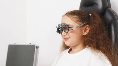 Küçük bir hasta, bir göz hastalıkları kliniğinde modern teşhis ekipmanları kullanan profesyonel bir optometrist tarafından göz testine tabi tutuluyor..