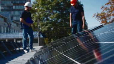 Güneş panellerinin kurulumu, bağlantısı ve montajı. İki işçi güneş panellerini bağlıyor. Teknisyenler metal standa güneş panelleri kuruyor. Bir evin çatısına PV güneş panelleri kuran işçiler.