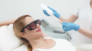Güzellik uzmanı soğutma jölesi sürerek lazer tüyü çıkarmaya hazırlanıyor. Modern bir klinikte profesyonel cilt bakımının ve güzellik tedavisinin aydınlatılması için ideal..