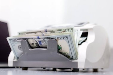Elektronik para sayma makinesindeki dolarların yakın plan çekimi, finansal hizmetleri, nakit yönetimini veya döviz kurunu resmetmek için ideal.                           