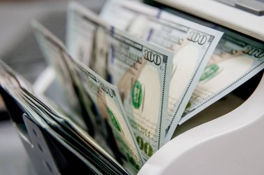 Elektronik para sayma makinesindeki dolarların yakın plan çekimi, finansal hizmetleri, nakit yönetimini veya döviz kurunu resmetmek için ideal.                           