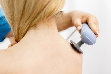 Genç bir kadın modern bir klinikte elektromanyetik terapi görüyor. Tedavi dokuların iyileşmesini hızlandırır, acıyı hafifletir ve kas gelişimini hızlandırır, genel sağlığa katkıda bulunur..