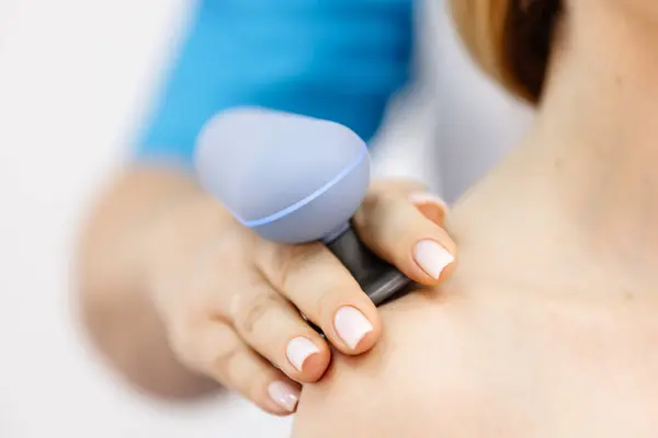 Genç bir kadın modern bir klinikte elektromanyetik terapi görüyor. Tedavi dokuların iyileşmesini hızlandırır, acıyı hafifletir ve kas gelişimini hızlandırır, genel sağlığa katkıda bulunur..