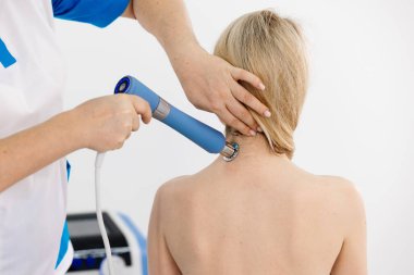 Fizyoterapist genç bir kadına şok dalgası terapisi uyguluyor. İyileşmeyi teşvik eden ve acıyı azaltan zararsız bir tedavi. Modern fizyoterapi tekniklerini ve tedavi yöntemlerini sergilemek için ideal..          