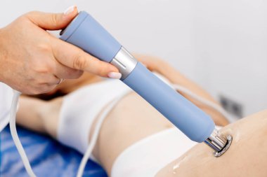 Fizyoterapist genç bir kadına şok dalgası terapisi uyguluyor. İyileşmeyi teşvik eden ve acıyı azaltan zararsız bir tedavi. Modern fizyoterapi tekniklerini ve tedavi yöntemlerini sergilemek için ideal..          