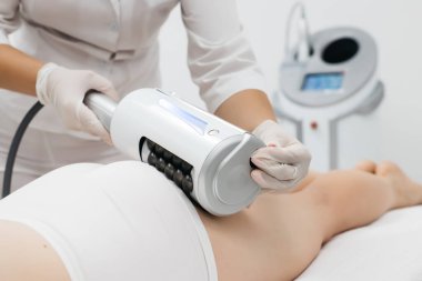 Derin selülit azaltımı ve vücut hatları için endosphere terapisi. Bir terapist cihazı modern bir klinikte uyguluyor, cilt yenilenmesini arttırıyor..