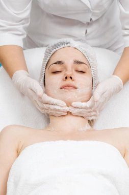 Kozmetik uzmanı modern bir güzellik kliniğinde gelişmiş cilt bakımı tekniklerini vurgulayan bir yüz kremi uyguluyor. Reklamınızda birinci sınıf spa tedavilerini sergilemek için ideal..     