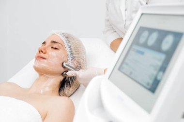 Kozmetik uzmanı yüz gençleştirme ve sıkma için RF kaldırma ameliyatı yapıyor. Bu müdahale etmeyen prosedür cildinizi sertleştirir ve pürüzsüzleştirir. Güzellik rutininizi geliştirir..